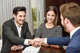 微笑的轻夫妇与保险代理人投资顾问握手桌子高清图片素材